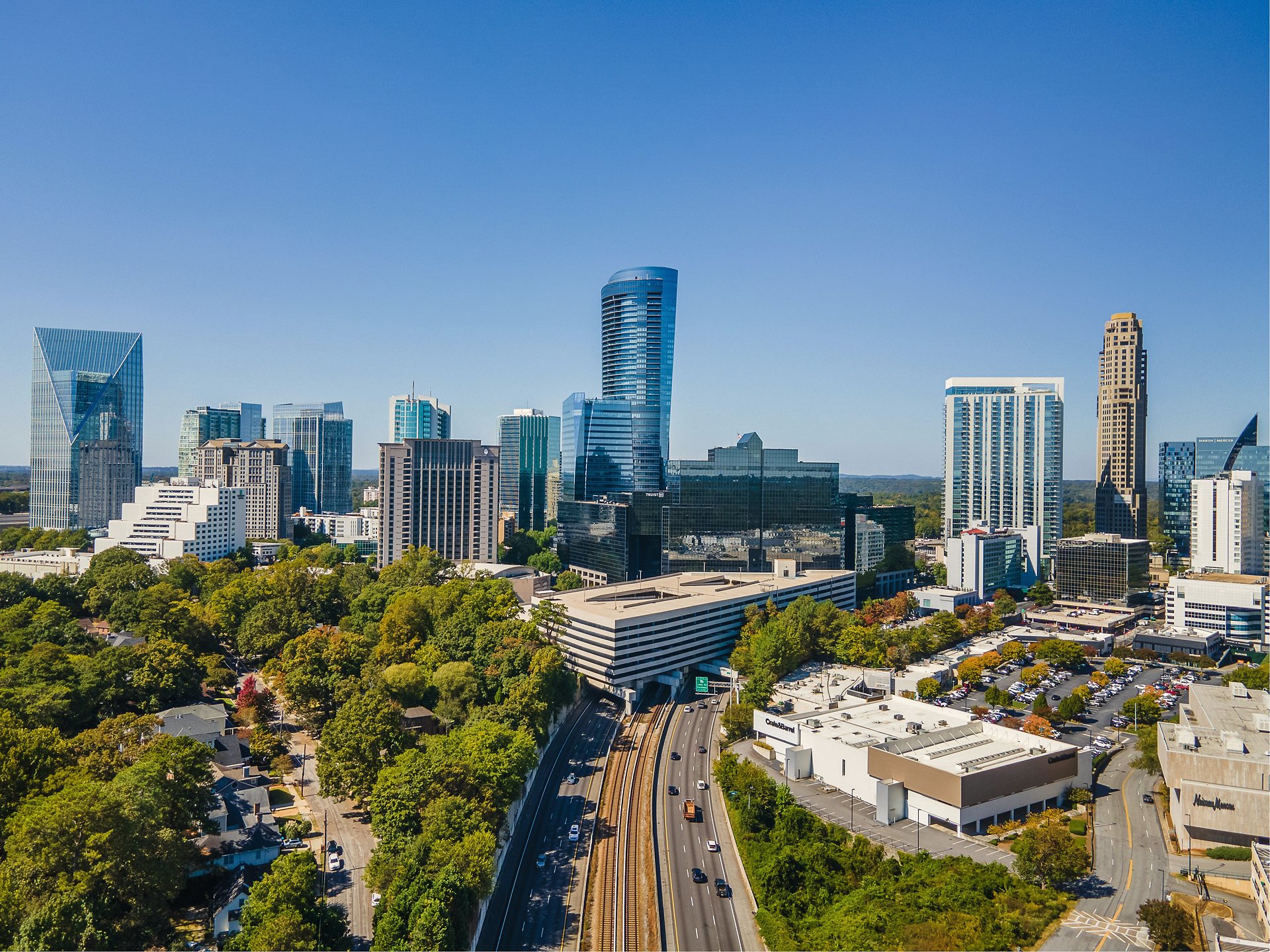 The Buckhead skyline in Atlanta, its towers rising above a dense tree canopy under a clear sky